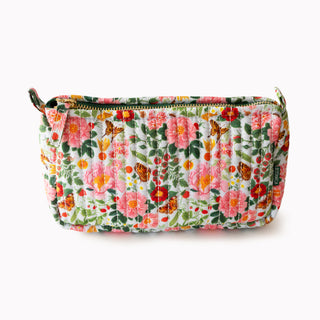 A quilted cosmetic pouch with a vibrant floral and butterfly pattern in pink, red, orange, and green on a white background, shown on a clean white studio background.