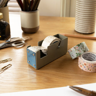Metal tape dispenser and illustrated tape on a wooden desk