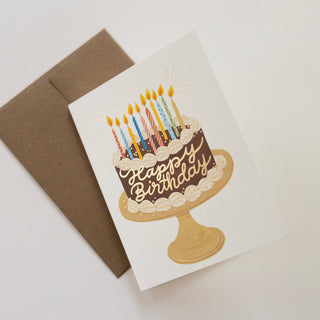 Chocolate Birthday Cake greeting card by Oana Befort for Botanica Paper Co. showcasing elegant watercolor chocolate cake illustration with botanical elements and luxurious gold foil details on premium matte cardstock
