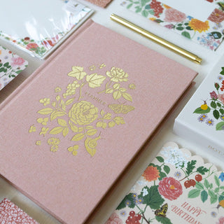 Close-up detail of Reverie planner cover by Oana Befort for Botanica Paper Co. showcasing the intricate gold foil lush floral stamping and matte gold foil-gilded edges on premium soft pink linen cloth