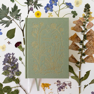 Botanica Paper Co.'s Herbarium planner artfully styled with dried pressed flowers and botanical specimens, highlighting the planner's unique herbarium concept for preserving nature's moments