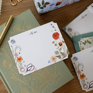 Close-up of an HERBARIUM notecard with delicate floral illustration, soft die-cut edge, and elegant vintage herbarium styling.