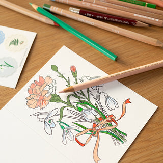 Coloring greeting card with floral design and colored pencils on a wooden surface