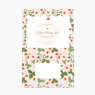Letter writing set by Botanica Paper Co. featuring a pink background decorated with strawberry and blooms patterns, with a central white oval label.