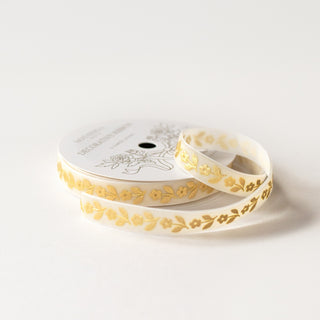 Gold daisy on cream white velvet ribbon on a spool and white background.