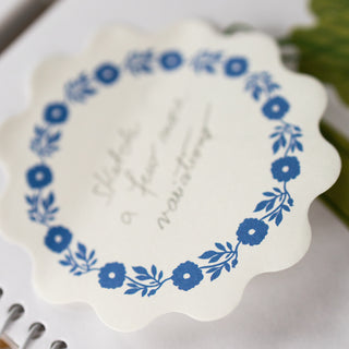 Details of sticky note with blue floral design and text on a white background
