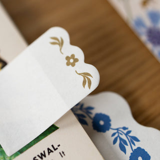 Close-up of a decorative sticky note with floral designs on a wooden surface.