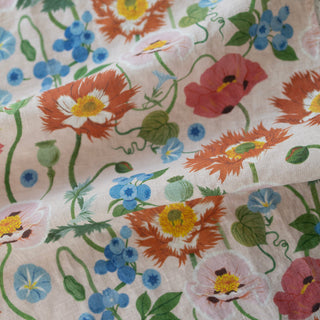 Close-up detail of the Poppies tea towel by Oana Befort showing the fine European linen weave and intricate poppy flower illustrations with delicate petal textures beautifully displayed against the gentle pink backdrop