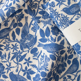 Close-up of the Songbirds tea towel by Oana Befort revealing the fine European linen texture and detailed blue songbird illustrations with delicate feather work and botanical elements printed with non-toxic inks
