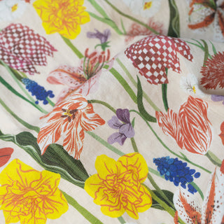 Close-up of the Spring tea towel by Oana Befort displaying individual spring botanical elements including delicate flower buds, fresh green stems, and the natural weave pattern of the linen fabric
