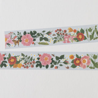 Two narrow strips of floral washi tape laid horizontally on a white textured background. The tape features a detailed botanical pattern with pink and red flowers, green leaves, small yellow and white blossoms, berries, and a butterfly.