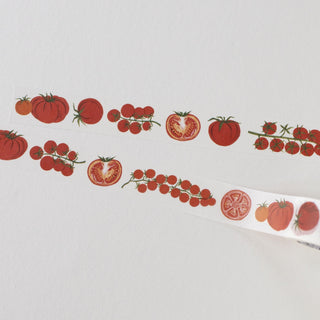 A close-up of a white decorative strip or paper tape printed with illustrated red tomatoes and tomato clusters on a plain light background.
