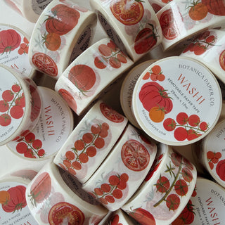 A pile of Botanica Paper Co. decorative washi tape rolls featuring a vintage-style tomato illustration.