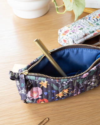 Floral-patterned pencil case with a gold pen on a wooden surface