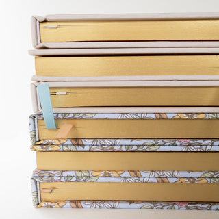 Side view showing the bottom side of a stack of Linen-Bound planners illustrated by Oana Befort for Botanica Paper Co.