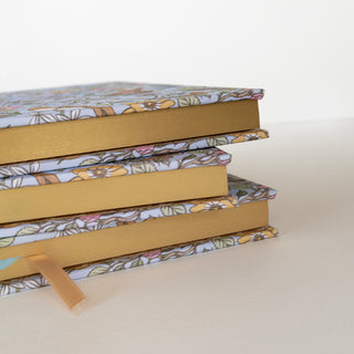 Side view of a stack of Songbirds Linen Bound Planners illustrated by Oana Befort for Botanica Paper Co.
